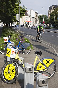 Austria, Vienna, Neubau District, Bicycles for use in city centre with approaching cyclist on road behind