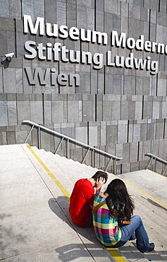 Austria, Vienna, Neubau District, Young student couple sitting on the steps of the Museum of Modern Art, Museum Moderner Kunst Stiftung Ludwig Wien or MUMOK