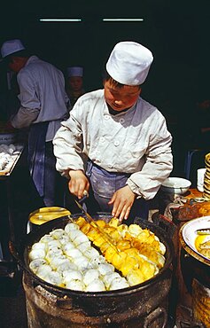 CHINA Shaanxi Province Xian Cook turning food frying in large pan in front of him.