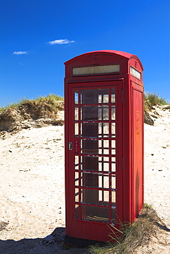 Traditional red British telephone box amongst the sand dunes of Studland Bay, Dorset, England, United Kingdom, Europe