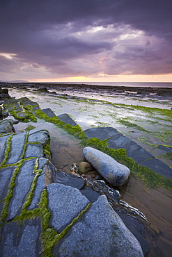 Stormy sunset over the Bristol Channel, viewed from the rocky shores of Kilve Beach, Somerset, England, United Kingdom, Europe