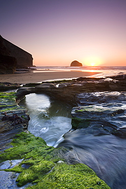 Water channel flowing beneath natural rock arch at Trebarwith Strand beach in Cornwall, England, United Kingdom, Europe