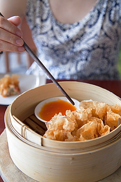 Woman eating prawn wrapped in fried rice paper at The Waterfront restaurant, Da Nang, Vietnam, Indochina, Southeast Asia, Asia