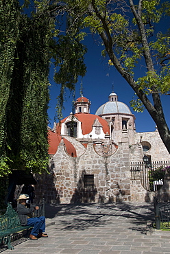 Local man resting on a park bench with Iglesia del Carmen in background, Morelia, Michoacan, Mexico, North America