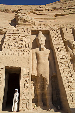 Local man at temple entrance, Ramses II statue on right, Hathor Temple of Queen Nefertari, Abu Simbel, UNESCO World Heritage Site, Egypt, North Africa, Africa