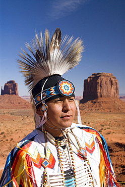 Navajo man dressed in a traditional costume, with Merrick Butte on the right and East Mitten Butte on the left in the background, Monument Valley Navajo Tribal Park, Utah, United States of America, North America