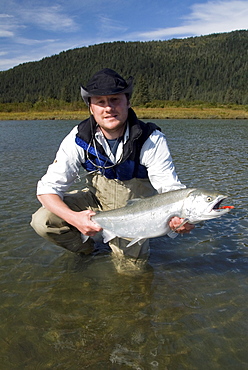 Fisherman holding a Silver (Coho) salmon (Oncorhynchus kisutch), Coghill Lake, Alaska, United States of America, North America