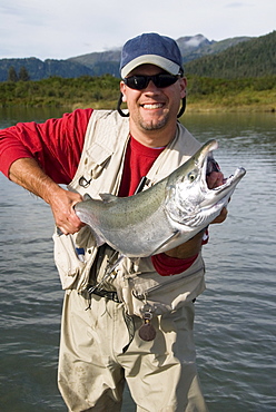 Fisherman holding a Silver (Coho) salmon (Oncorhynchus kisutch), Coghill Lake, Alaska, United States of America, North America