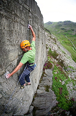 A rock climber makes a first ascent of on the cliffs above the Llanberis Pass, Snowdonia National Park, Wales, United Kingdom