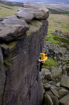 Climber makes a solo ascent of one of the thousands of classic outcrop climbs on the popular cliff of Stanage Edge, near Hathersage, Peak District, Derbyshire, England, United Kingdom, Europe