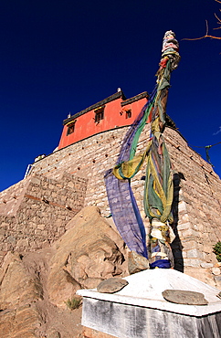 A stupa bound with prayer flags stands under the walls of Leh Palace, Leh, Indus Valley, Ladakh, India, Asia