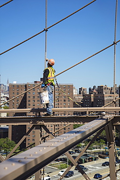 Workman repainting beams and cables on Brooklyn Bridge, New York City, New York, United States of America, North America