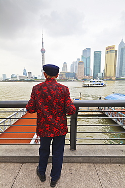 A man looking at the Pudong skyline from the Bund across the Huangpu River, Shanghai, China, Asia