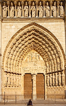 Woman praying in front of Last Judgment gate, west front, Notre Dame Cathedral, UNESCO World Heritage Site, Paris, France, Europe