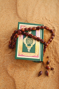 Koran and prayer beads in sand, Dubai, United Arab Emirates, Middle East