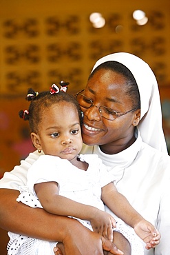 Franciscan sister holding an orphan at nursery and kindergarten run by Catholic nuns, Lome, Togo, West Africa, Africa