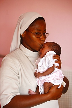 Franciscan sister holding an orphan at nursery and kindergarten run by Catholic nuns, Lome, Togo, West Africa, Africa