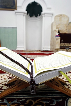 An open Holy Quran and a Muslim prayer beads on wood stand with mihrab in background, Hanoi, Vietnam, Indochina, Southeast Asia, Asia