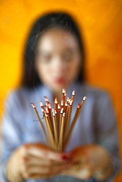 Woman praying with incense sticks in hands, Thien Hung Buddhist temple, Ho Chi Minh City (Saigon), Vietnam, Indochina, Southeast Asia, Asia