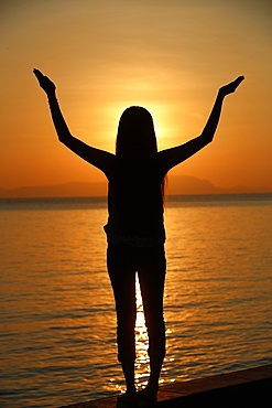 Silhouette of a woman standing by the sea at sunset doing yoga pose and meditation, Kep, Cambodia, Indochina, Southeast Asia, Asia