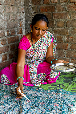 Adivasi woman sticking beads onto a sari in a village in Narmada district, Gujarat, India, Asia