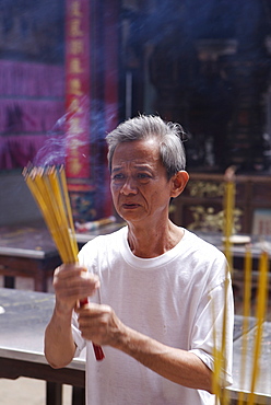 Local man making an offering in a Buddhist temple, Ho Chi Min City, Vietnam, Indochina, Southeast Asia, Asia