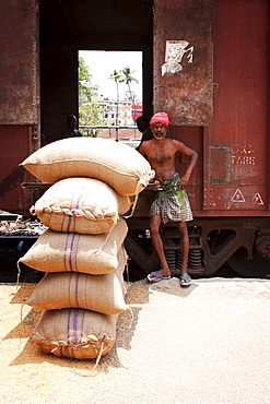 Depot worker unloading rice sacks from train, Kerala, India, Asia