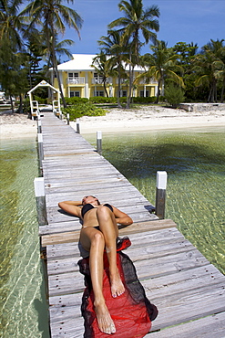 An American model sunbathing on the jetty of the harbour beach of Abaco Main Island, Bahamas, West Indies, Caribbean, Central America