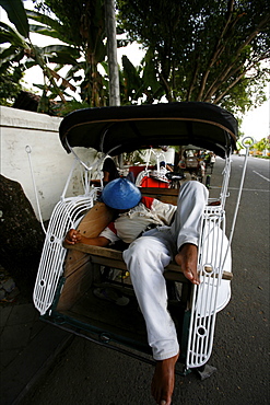 A tuk tuk driver sleeeping in front of the Prambanan temple, Java, Indonesia, Southeast Asia, Asia