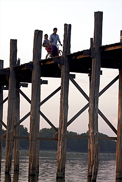 Cyclist on the U Bein teak bridge, Amarapura, Mandalay, Myanmar (Burma), Asia