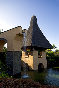 Water cascade and thatched roof beside a pool, Baie aux Tortues, Pointe aux Pimentes, Mauritius, Africa