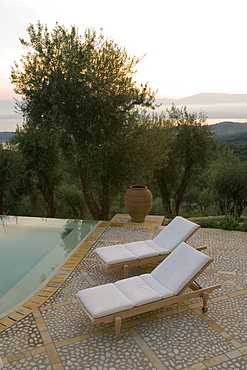 Sun loungers and pot on terrace beside infinity pool at dusk, Kerkyra, Corfu, Ionian Islands, Greek Islands, Greece, Europe