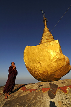 Monk praying on Kyaiktiyo Pagoda known as golden rock on top of Mount Kyaiktiyo, Myanmar, Asia