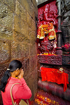 Pilgrim in front of a red coloured stone statue in the Kamakhya Hindu temple, Guwahati, Assam, India, Asia