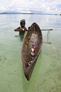 Young boy goes fishing with his canoe and harpoon, Marovo lagoon, Solomon Islands, Pacific