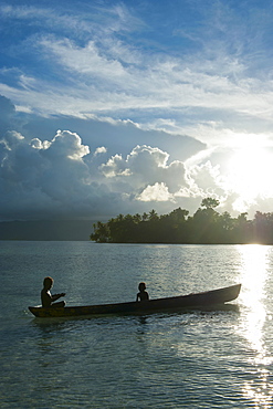 Boys in a canoe in backlit in the Marovo Lagoon, Solomon Islands, Pacific