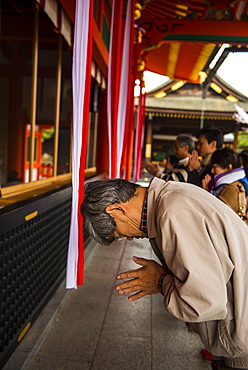 Praying pilgrim in the Endless Red Gates of Kyoto's Fushimi Inari Shrine, Kyoto, Japan, Asia