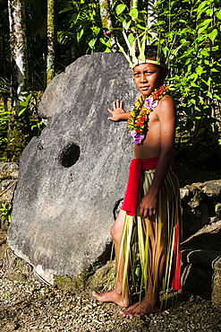 Young boy in traditional dress on the island of Yap standing before a huge stone money, Federated States of Micronesia, Caroline Islands, Pacific