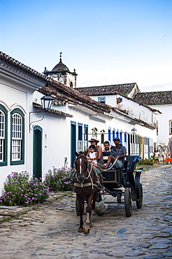 Horse cart with tourists riding through the town of Paraty, Rio de Janeiro, Brazil, South America