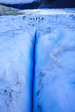 Tourists hiking above a giant crack on Fox Glacier, Westland Tai Poutini National Park, South Island, New Zealand, Pacific