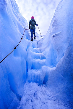 Woman walking steps out of a ice cave in Fox Glacier, Westland Tai Poutini National Park, South Island, New Zealand, Pacific