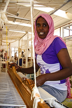 Friendly woman working on a hand weaving loom on a social project in the highlands of Eritrea, Africa