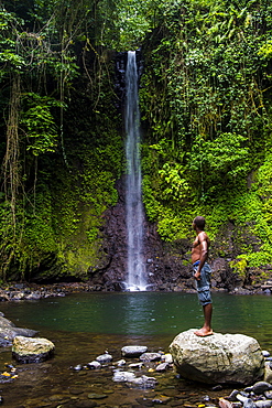 Man looking at the waterfall cascade Bombaim in the jungle interior of Sao Tome, Sao Tome and Principe, Atlantic Ocean, Africa