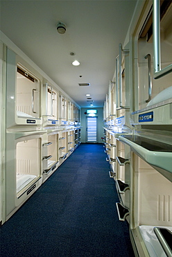 Rows and stacks of sleeping compartments along one corridor at a capsule hotel in Osaka, Japan, Asia