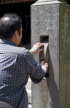 Man spinning a prayer wheel at Zenkoji Temple, Nagano City, Japan, Asia