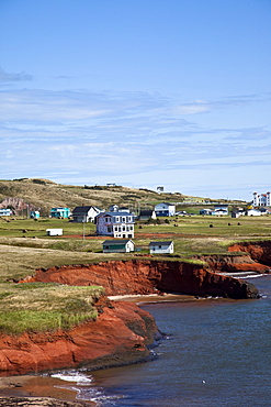 Scalloped red sandstone cliffs with houses perched on the top on the island of Havre-Aubert, Iles de la Madeleine (Magdalen Islands), Quebec, Canada, North America