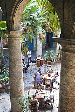 People sitting at tables and musicians playing in courtyard of colonial building built in 1780, Havana, Cuba, West Indies, Central America