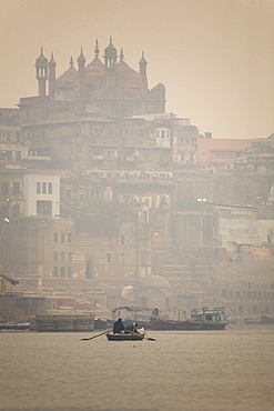 A boat is rowed on a typically foggy morning in the Ganga (Ganges) River at Varanasi, Uttar Pradesh, India, Asia