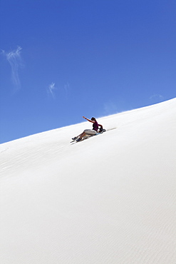 A woman rides a sandboard, sandboarding on a white sand dune, Lancelin, Western Australia, Australia, Pacific