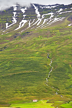 Farm house at the base of the mountains surrounding Neskapustadur, a fjord town in the east, Iceland, Polar Regions